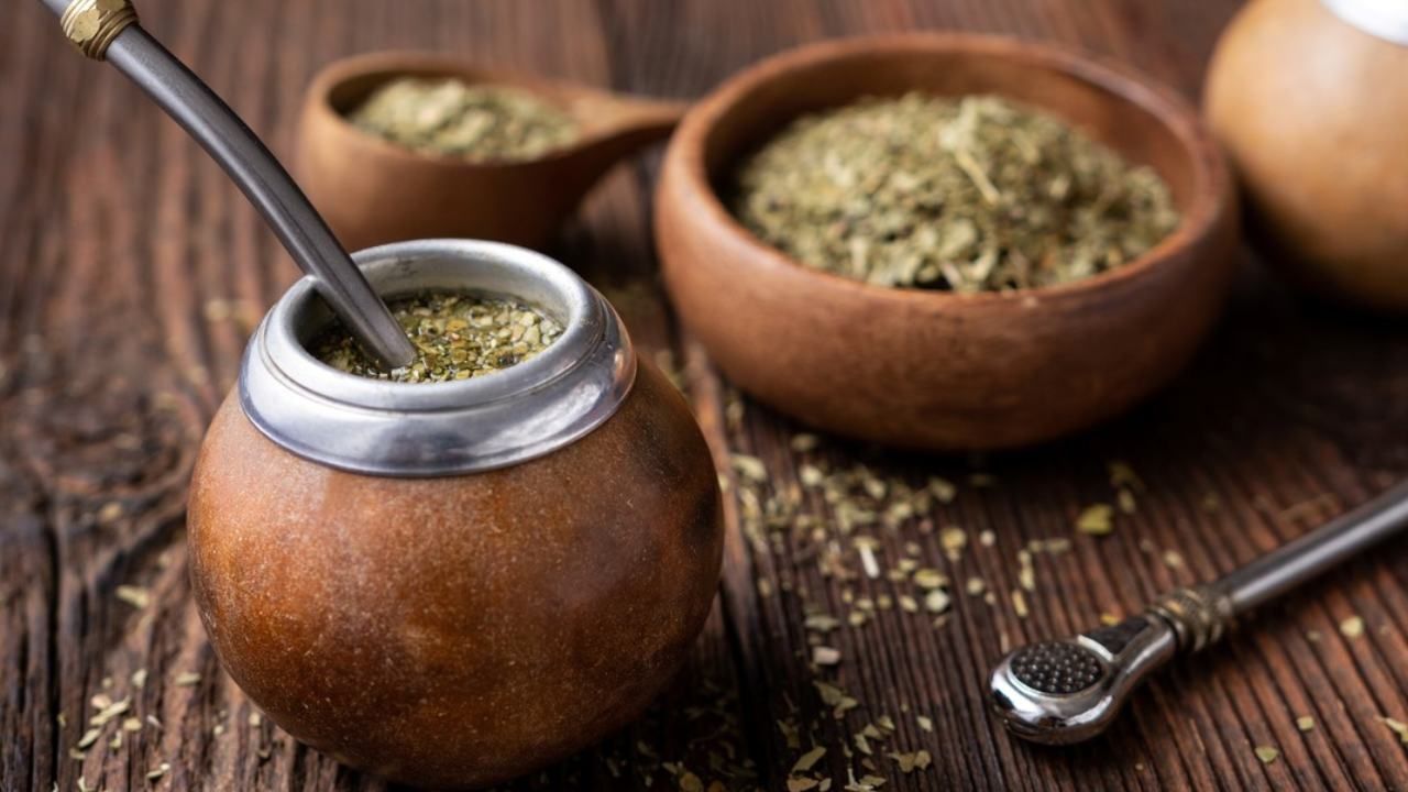 Mate gourds filled with yerba mate, on top of a wooden table.