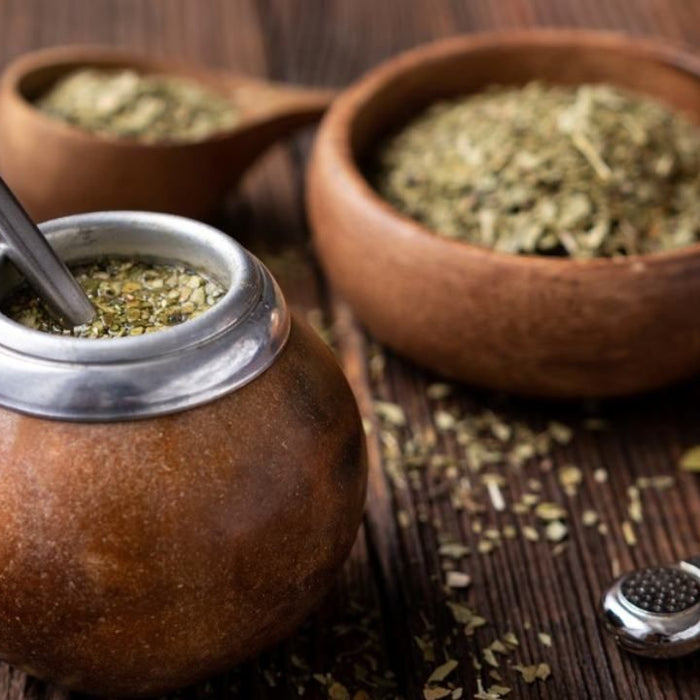 Mate gourds filled with yerba mate, on top of a wooden table.